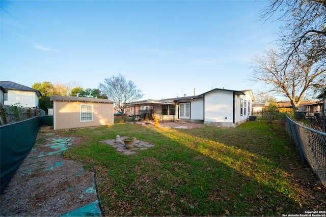 back of house featuring a patio, a yard, an outbuilding, an outdoor fire pit, and cooling unit