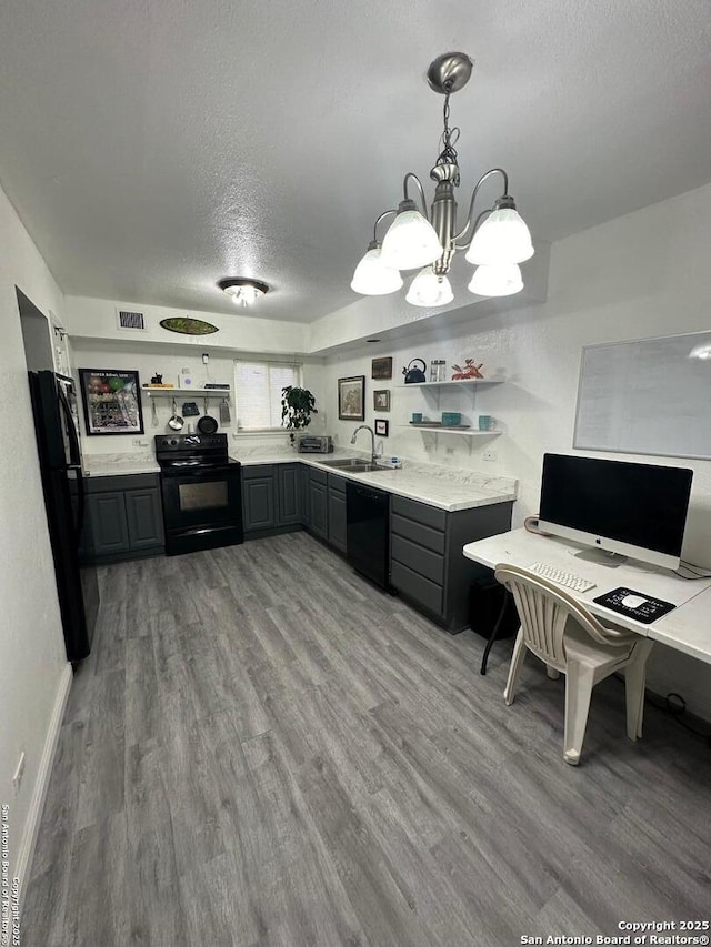 kitchen featuring kitchen peninsula, a textured ceiling, a chandelier, hanging light fixtures, and black appliances