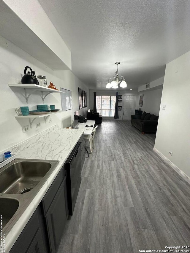 kitchen featuring hardwood / wood-style floors, pendant lighting, a textured ceiling, black dishwasher, and an inviting chandelier