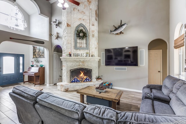 living room with a high ceiling, a fireplace, and ceiling fan