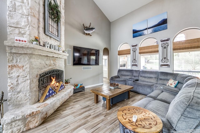 living room with high vaulted ceiling, a fireplace, and hardwood / wood-style floors