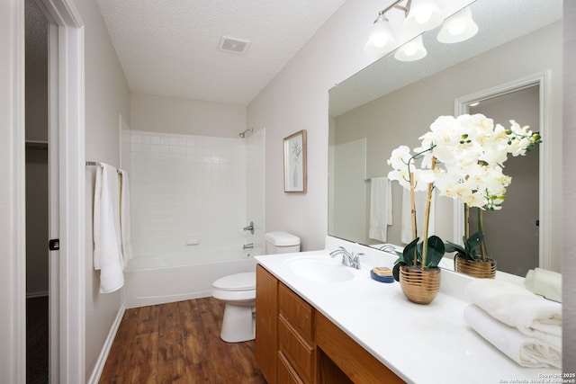 full bathroom featuring toilet, vanity, bathing tub / shower combination, hardwood / wood-style flooring, and a textured ceiling