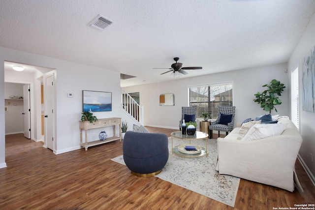 living room featuring dark wood-type flooring, a textured ceiling, and ceiling fan