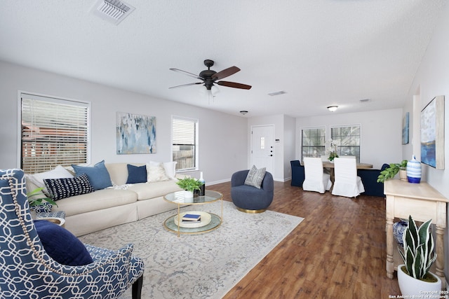 living room featuring a healthy amount of sunlight, ceiling fan, a textured ceiling, and dark hardwood / wood-style floors