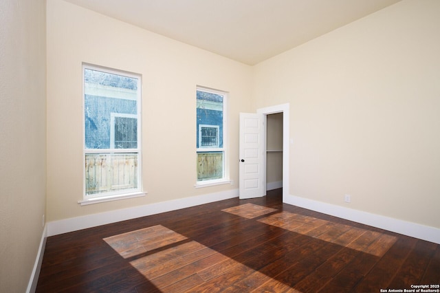 unfurnished room featuring a healthy amount of sunlight and dark hardwood / wood-style floors