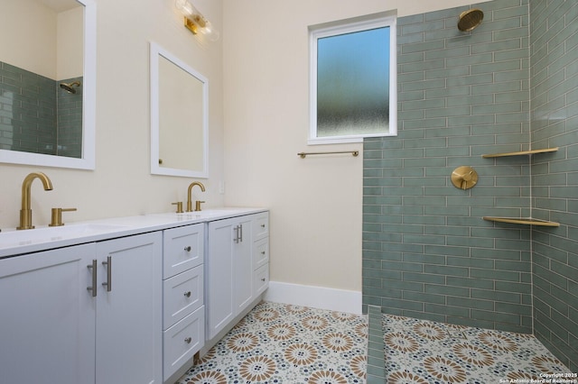 bathroom with tile patterned flooring, a tile shower, and vanity