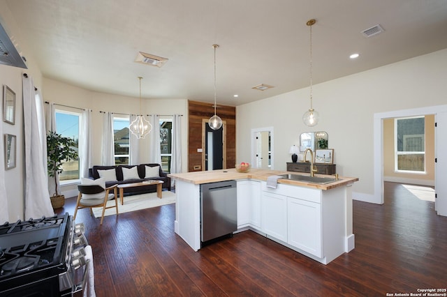 kitchen with a center island with sink, hanging light fixtures, stainless steel dishwasher, and sink