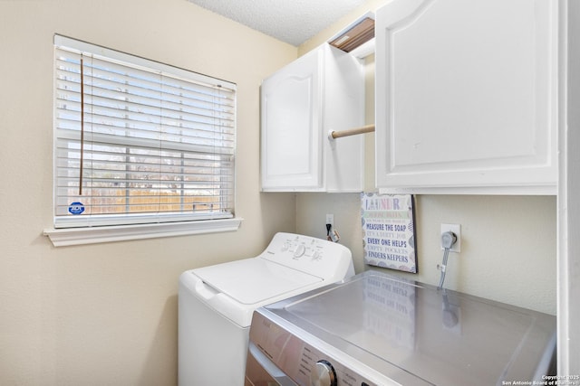 laundry room with washing machine and dryer, a textured ceiling, and cabinets