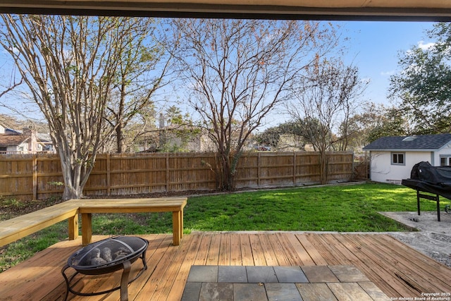 wooden deck with an outdoor fire pit and a lawn