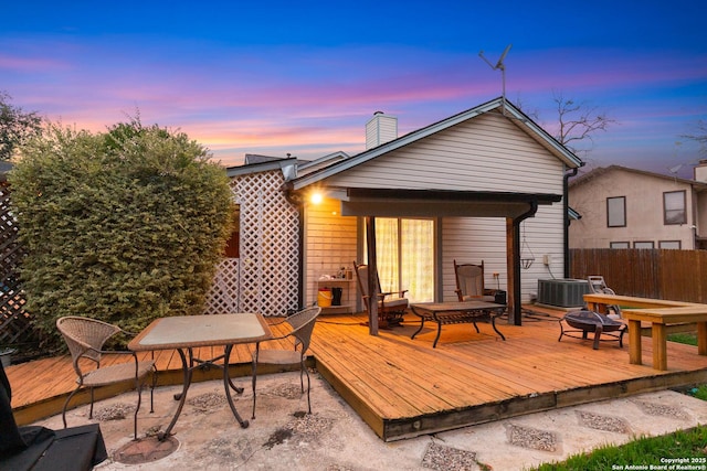 deck at dusk with cooling unit and an outdoor fire pit