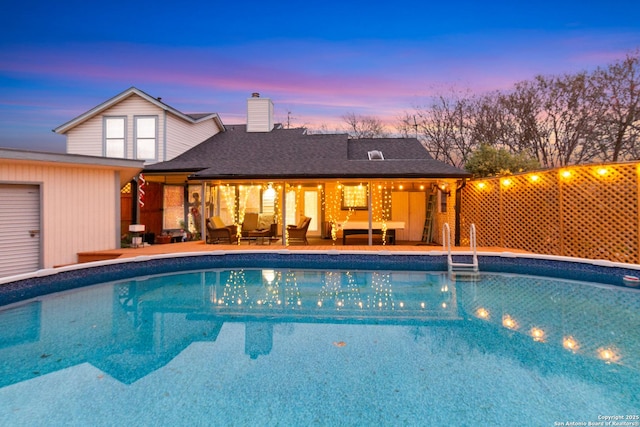 pool at dusk with a patio area and an outdoor living space