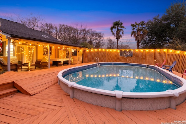 pool at dusk featuring a wooden deck