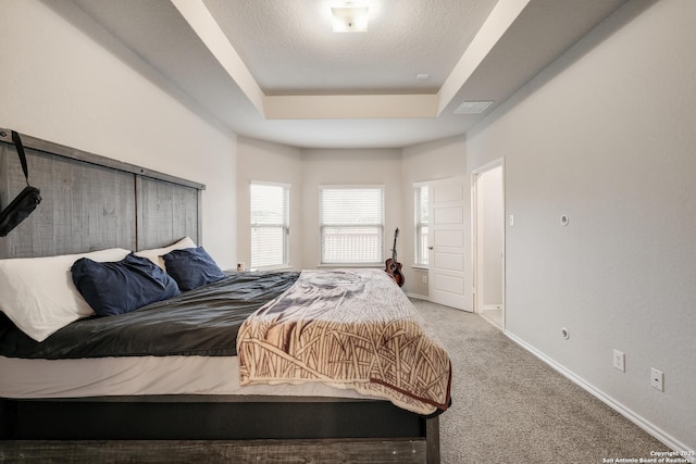 carpeted bedroom with a raised ceiling and a textured ceiling