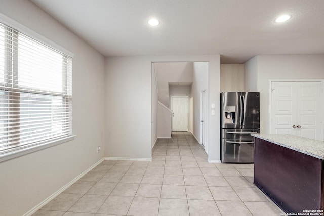 kitchen featuring light stone counters, stainless steel fridge with ice dispenser, and light tile patterned floors