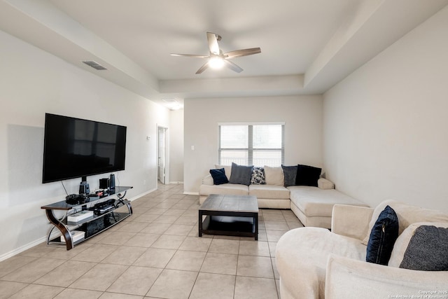 living room featuring light tile patterned floors, ceiling fan, and a tray ceiling