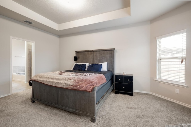 carpeted bedroom featuring multiple windows, connected bathroom, and a raised ceiling