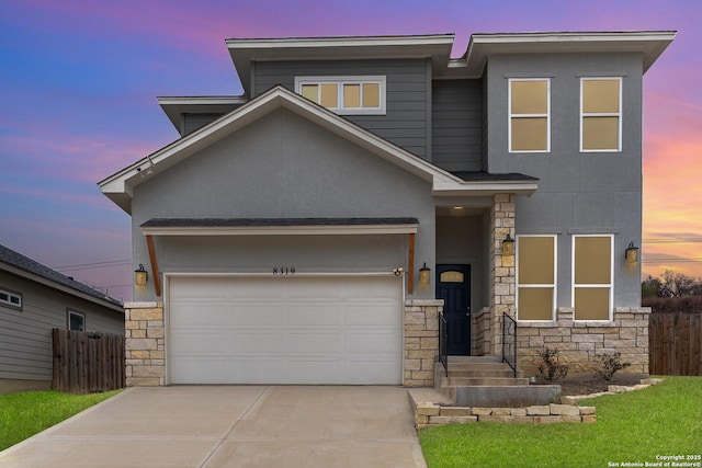 view of front of home with stone siding, fence, driveway, and stucco siding