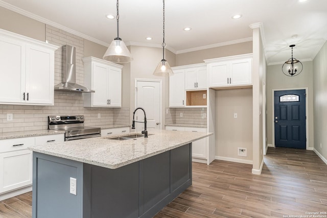 kitchen with wall chimney exhaust hood, a center island with sink, white cabinetry, stainless steel electric range oven, and sink