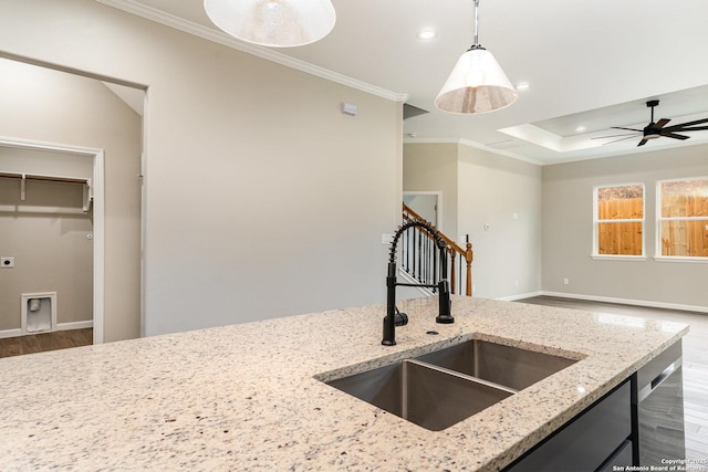 kitchen featuring sink, dishwasher, light stone counters, hanging light fixtures, and crown molding