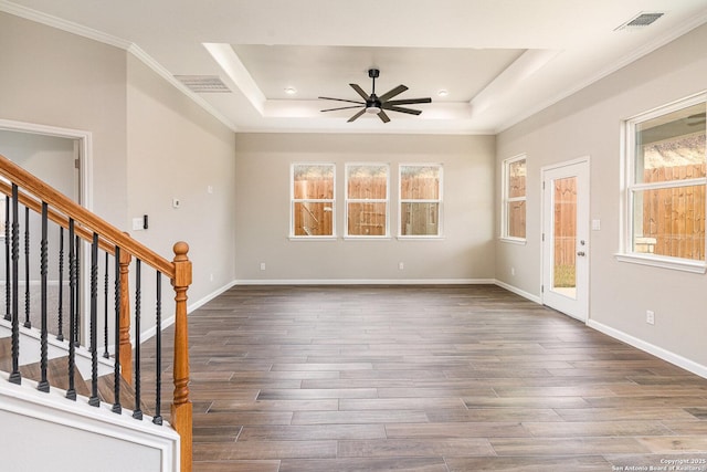 entrance foyer with ceiling fan, dark wood-type flooring, ornamental molding, and a raised ceiling