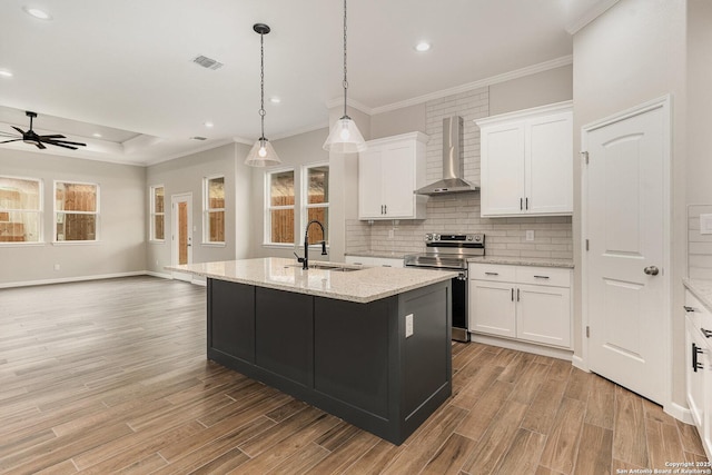 kitchen featuring sink, white cabinetry, stainless steel electric range oven, a center island with sink, and wall chimney range hood