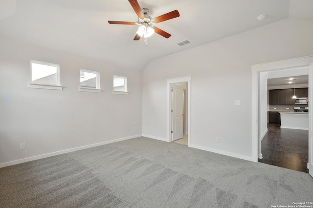 spare room featuring ceiling fan, vaulted ceiling, and dark carpet