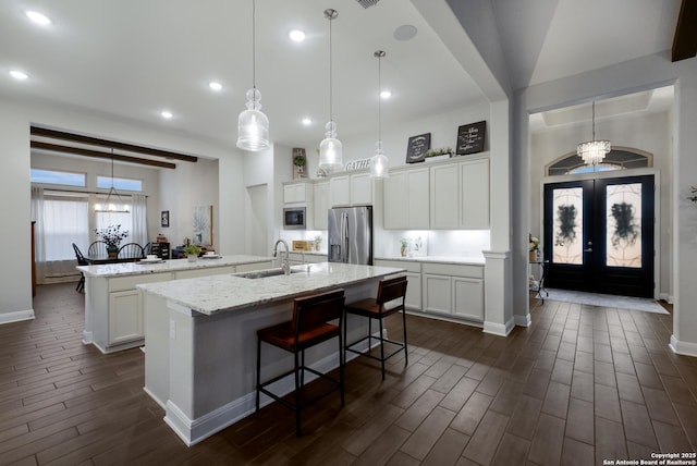 kitchen featuring pendant lighting, appliances with stainless steel finishes, sink, and a kitchen island with sink