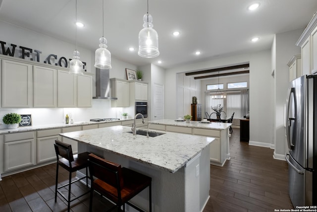 kitchen featuring a kitchen bar, sink, an island with sink, pendant lighting, and stainless steel appliances