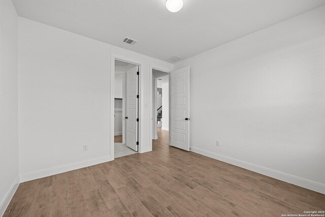 9314 Everly Crk, San Antonio, TX 78263 - unfurnished bedroom with wood finished floors, a walk in closet, baseboards, and visible vents