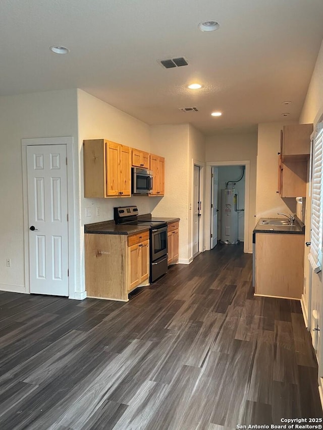 kitchen with appliances with stainless steel finishes, dark wood-type flooring, electric water heater, and light brown cabinets