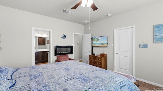 carpeted bedroom with ensuite bathroom and ceiling fan