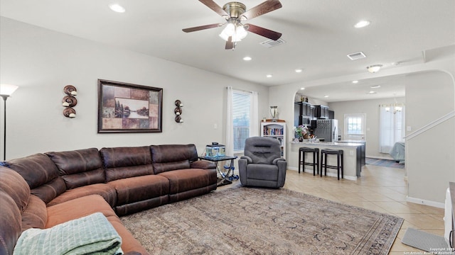 living room with ceiling fan with notable chandelier and light tile patterned floors