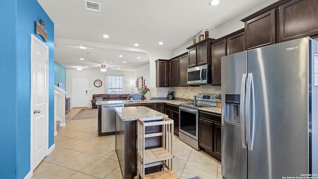 kitchen featuring kitchen peninsula, a center island, stainless steel appliances, light tile patterned floors, and dark brown cabinets