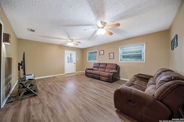 living room featuring a textured ceiling, ceiling fan, and light wood-type flooring