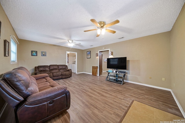 living room featuring a textured ceiling, hardwood / wood-style floors, ceiling fan, and independent washer and dryer