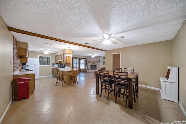 dining space featuring light tile patterned floors, a fireplace, beam ceiling, a textured ceiling, and ceiling fan with notable chandelier