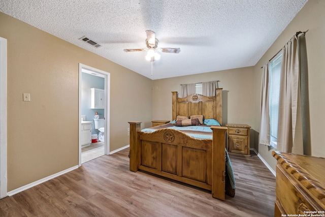 bedroom featuring ensuite bath, a textured ceiling, ceiling fan, and light wood-type flooring