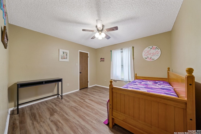 bedroom with ceiling fan, light wood-type flooring, and a textured ceiling