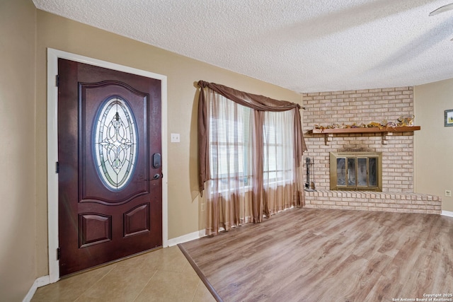 entryway with a textured ceiling, light hardwood / wood-style floors, and a fireplace