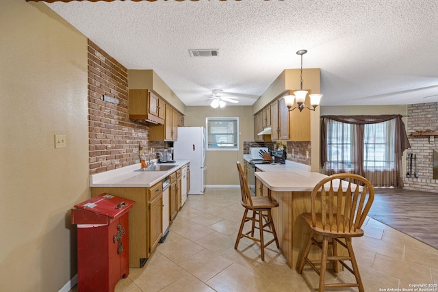 kitchen with sink, decorative light fixtures, a textured ceiling, white appliances, and tasteful backsplash