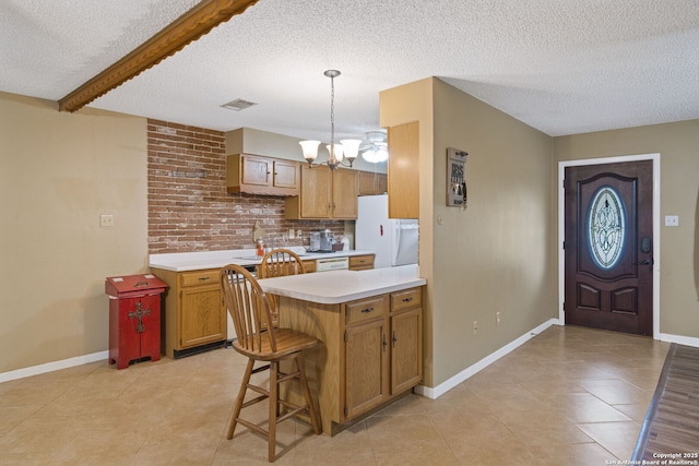 kitchen with a breakfast bar area, beamed ceiling, a notable chandelier, white refrigerator, and decorative light fixtures