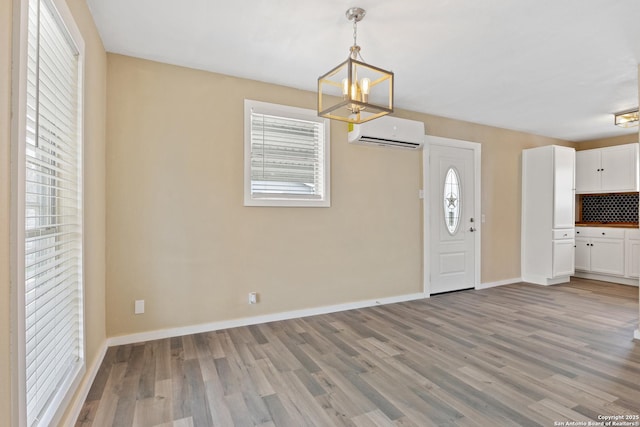 entryway with a notable chandelier, light hardwood / wood-style floors, and a wall mounted air conditioner