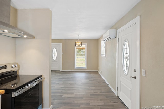 kitchen with a wall unit AC, hanging light fixtures, stainless steel electric stove, wall chimney range hood, and wood-type flooring