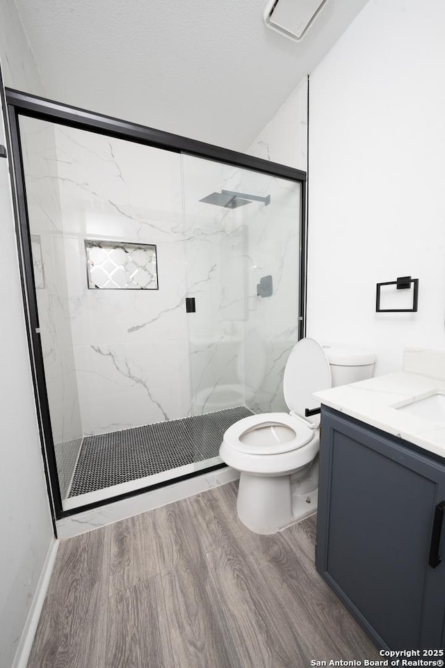 bathroom with toilet, an enclosed shower, vanity, and hardwood / wood-style flooring