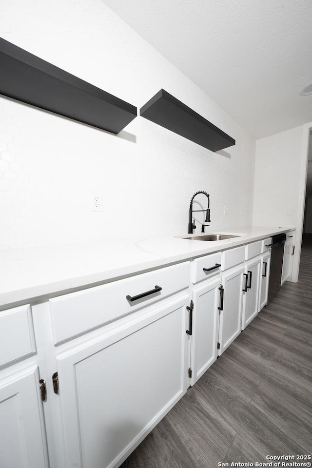 kitchen with sink, white cabinets, light stone counters, black dishwasher, and dark hardwood / wood-style flooring