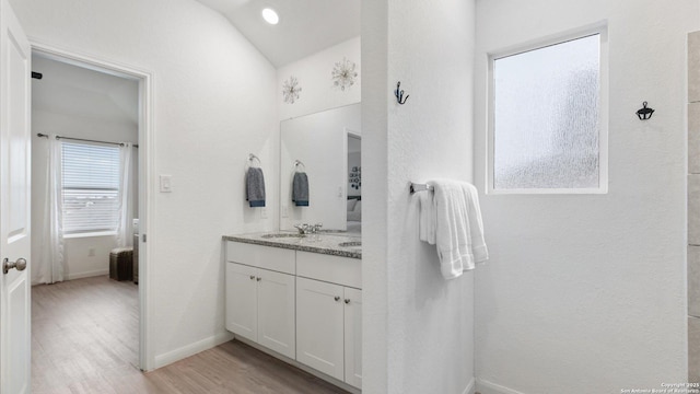 bathroom featuring hardwood / wood-style flooring, vaulted ceiling, and vanity