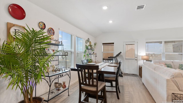 dining room with light wood-type flooring, a wealth of natural light, and lofted ceiling