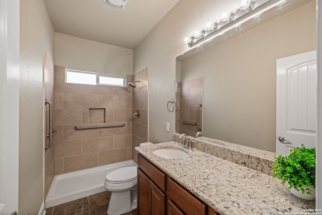 bathroom with toilet, a tile shower, and vanity