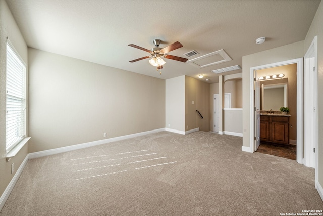 unfurnished bedroom with a textured ceiling, carpet floors, ceiling fan, and connected bathroom