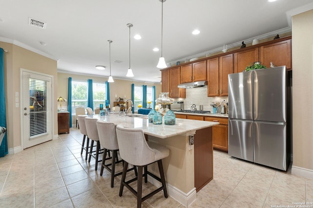 kitchen featuring stainless steel appliances, ornamental molding, pendant lighting, an island with sink, and a breakfast bar